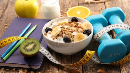 Foto de Concepto de alimentos dietéticos tazón de avena y frutas con dumbbell- concepto de alimentos saludables - Imagen libre de derechos