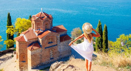 Foto de Mujer en vestido blanco disfrutando de la vista de la famosa iglesia, lago Ohrid en Macedonia - Imagen libre de derechos