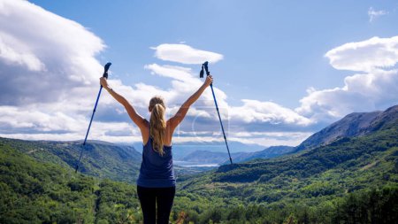 Foto de Logro, éxito de escalada, concepto de vista impresionante mujer excursionista en la parte superior con los brazos abiertos disfrutando de vistas panorámicas a la montaña y al bosque - Imagen libre de derechos
