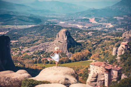 Foto de Mujer vestida de blanco disfrutando de una vista panorámica del paisaje y el monasterio de Meteoro - Viajes, turismo turístico en Grecia - Imagen libre de derechos