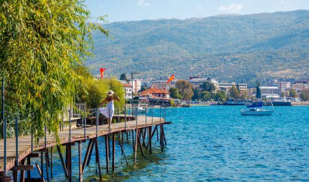 Photo for Travel destination, Tour tourism in Macedonia- Woman walking on wooden bridge on Ohrid lake - Royalty Free Image