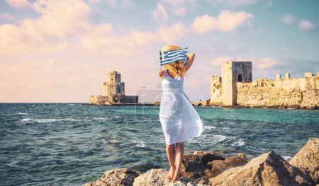 Photo for Woman in white dress, holding greek flag traveling in Europe- Greece, Peloponese- Methoni castle - Royalty Free Image