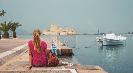 Foto de Mochilera sentada en el puerto de Nafplio, mirando el castillo de Bourtzi Grecia - Imagen libre de derechos
