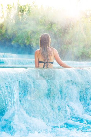 Téléchargez les photos : Jeune touriste profitant d'un spa naturel avec cascades dans les thermes Saturnia Toscane en Italie- Source chaude, bien-être, soins de santé - en image libre de droit