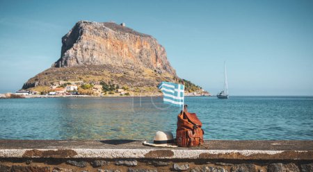 Foto de Viaje Grecia concepto- bolsa, sombrero de verano y bandera en el mar y la isla griega - Imagen libre de derechos