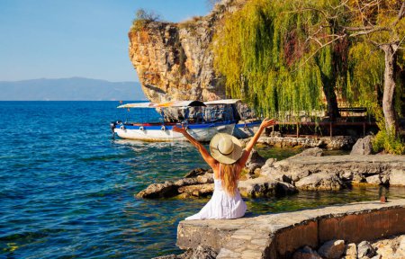 Téléchargez les photos : Voyage, vacances ou tour tourisme en Macédonie- Lac d'Ohrid et touriste femelle en robe blanche jouit paysage typique - en image libre de droit