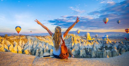 Photo for Happy woman enjoying panoramic view of Cappadocia landscape and colorful hot air balloons in the sky- Travel destination concept Turkey - Royalty Free Image