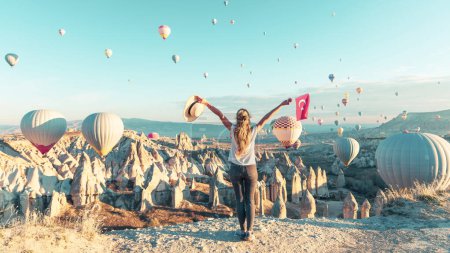 Téléchargez les photos : Jeune touriste féminine regardant ballon à air chaud coloré survolant le paysage de la Cappadoce Voyage, vacances, tourisme d'excursion en Turquie - en image libre de droit
