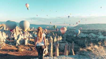 Foto de Joven turista buscando colorido globo aerostático volando sobre el paisaje de Capadocia- Viajes, vacaciones, turismo turístico en Turquía - Imagen libre de derechos