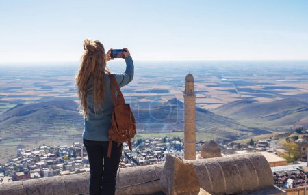 Woman taking photography on roof dome, panoramic view of Madrin city in Turkey