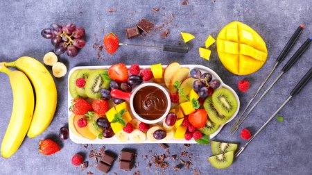 Foto de Maceta de fondue de chocolate con varias frutas frescas - Imagen libre de derechos