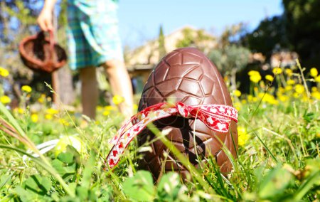 Foto de Huevo de Pascua en hierba verde con niño sosteniendo cesta de mimbre - Imagen libre de derechos