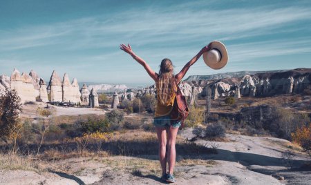 Téléchargez les photos : Heureuse touriste femme en Cappadoce avec les bras levés et paysage de la vallée de l'amour-Turquie - en image libre de droit