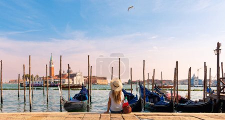 Photo for Woman tourist sitting and looking typical gondola on the canal- Venice, Italy - Royalty Free Image