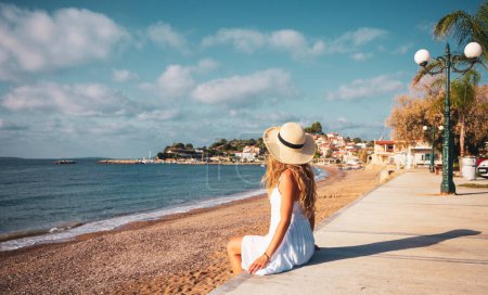 Téléchargez les photos : Jeune femme assise sur la plage jouissant d'une belle vue - en image libre de droit
