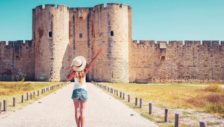 Téléchargez les photos : Murs de ville célèbres français- Aigues Mortes- Touriste WOman avec chapeau bleu profitant mur environnant - en image libre de droit