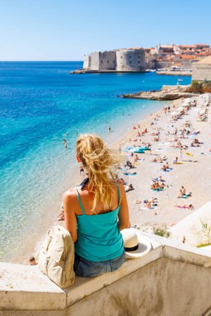 Foto de Turista femenina serena mirando al casco antiguo de Dubrovnik y hermosa playa, destino de viaje croata, vacaciones, turismo turístico - Imagen libre de derechos