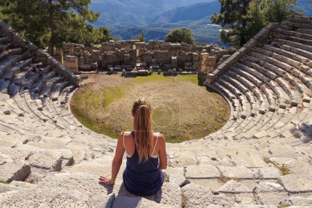 Mujer viajera sentada en anfiteatro en Turquía- Antalya, Arykanda