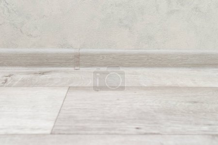 Photo for Linoleum wooden floor and plastic skirting board. - Royalty Free Image