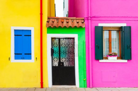 Photo for Yellow and pink painted facades of the houses and windows with colorful shutters. Colorful architecture in Burano island, Venice, Italy. - Royalty Free Image