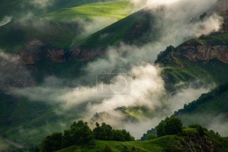 Photo for Morning fog in the mountains at sunrise. Clouds over the green mountains and hills. Beautiful summer landscape. Gil-Su valley in North Caucasus, Russia. - Royalty Free Image