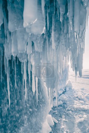 Téléchargez les photos : Grotte de glace avec glaçons sur le lac Baikal au coucher du soleil. Glace bleue au soleil du soir. Paysage hivernal du lac Baïkal, Sibérie, Russie - en image libre de droit