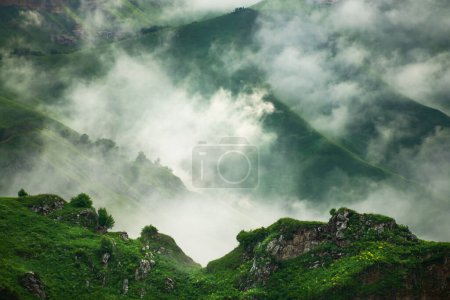 Niebla matutina en las montañas al amanecer. Nubes sobre las verdes montañas y colinas. Paisaje de verano. Valle de Gil-Su en el norte del Cáucaso, Rusia.