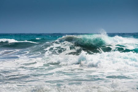 Wellen am Strand bei windigem Wetter. Insel Santorin, Griechenland. Blaues Meer und blauer Himmel.