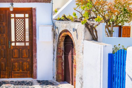 Weiße kykladische Architektur auf der Insel Santorin, Griechenland. Holztüren und dekorative Bäume im Hof