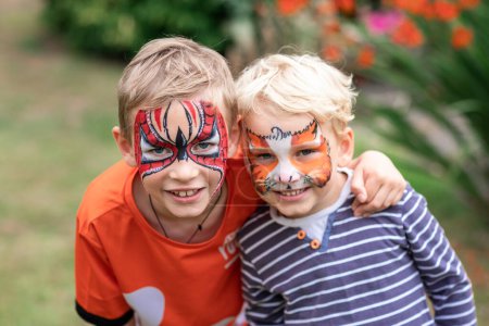 Two happy cute little boys with their faces painted. Face painting, kids painting face at the birthday party or on holidays