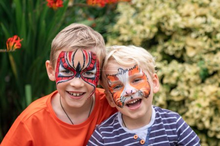 Two happy cute little boys with their faces painted. Face painting, kids painting face at the birthday party or on holidays