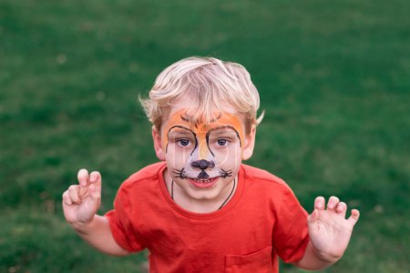 Cute little boy with face paint. Face painting, kid painting face at the birthday party or on holidays