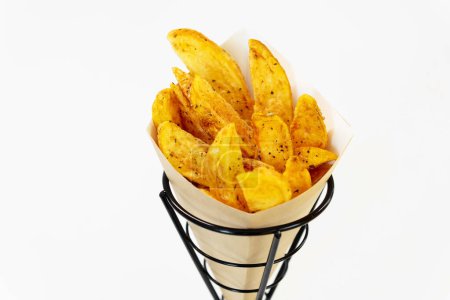 Téléchargez les photos : Oven baked potato wedges with sea salt and herbs. fries in a recyclable paper bag, popular fast street food - en image libre de droit