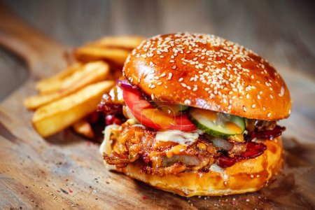 Téléchargez les photos : Burger juteux avec côtes de porc, sauce épicée et légumes frais sur planche à découper en bois - en image libre de droit