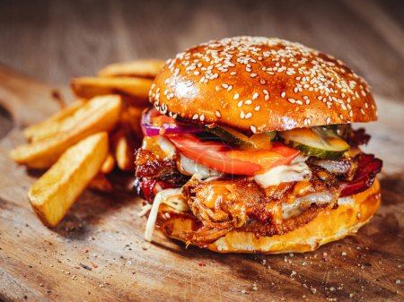 Téléchargez les photos : Burger avec côtes de porc, sauce épicée et légumes frais sur planche à découper en bois - en image libre de droit