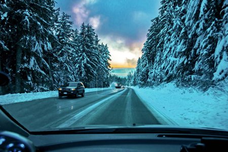 La route d'hiver glacée menant aux pistes de ski des montagnes Seymour traverse une forêt enneigée, des voitures et un camion balayeur de neige se déplacent sur la route, le parc provincial Mountain Seymour
