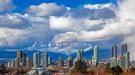 Photo for New residential area of  high-rise buildings in the city of Burnaby, construction site in the center of the city against the backdrop of snow covered mountain range and blue cloudy sky - Royalty Free Image