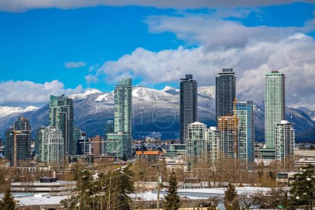Photo for New residential area of  high-rise buildings in the city of Burnaby, construction site in the center of the city against the backdrop of snow covered mountain range and blue cloudy sky - Royalty Free Image