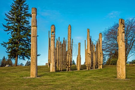 Photo for Native American Indian First Nations totem poles in Burnaby Mountain Park Totem poles and tall trees against of blue sky - Royalty Free Image