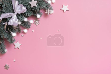 Pine trees branches with Christmas New Year decoration top view, flat lay on pink background with copy space. Blank greeting card.