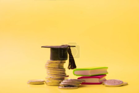 Photo for Graduated cap with coins and books on yellow background. Savings for education concept. - Royalty Free Image