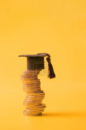 Photo for Graduated cap with coins on orange background. Savings for education concept. Copy space. - Royalty Free Image