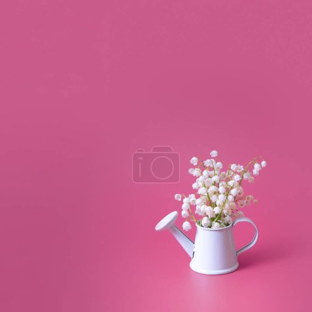 Blank greeting card with lilies of the valley bouquet in a decorative watering can on a magenta background.
