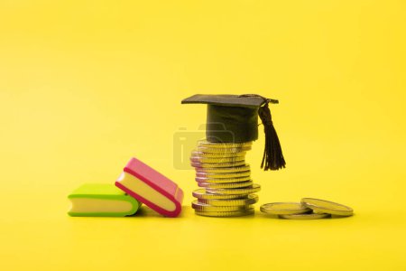 Graduated cap with coins on yellow background. Savings for education or financial literacy concept.