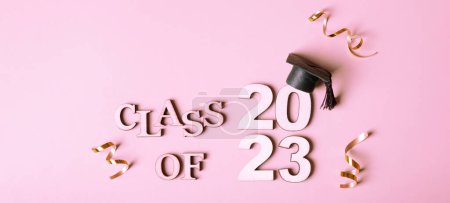 Class of 2023 concept. Wooden number 2023 with graduated cap on pink background.