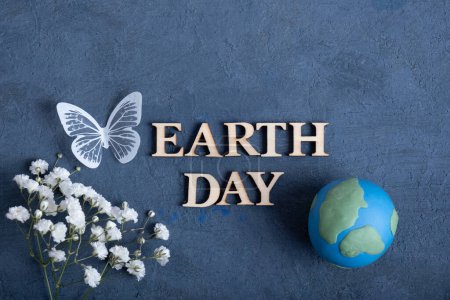Téléchargez les photos : Texte du jour de la Terre avec globe, fleurs et papillon. Happy Earth day concept plat, vue de dessus. - en image libre de droit