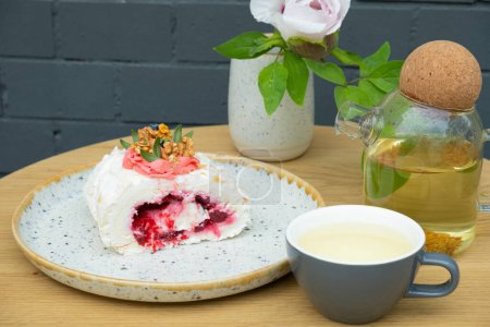 Téléchargez les photos : Rouleau de meringue avec thé sur une table dans un café. Aliments sucrés nature morte. - en image libre de droit