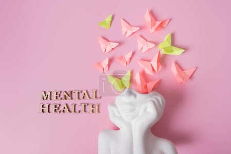 Foto de Una figura de una cabeza con mariposas sobre un fondo rosa. Concepto de salud mental. - Imagen libre de derechos