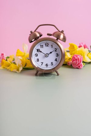 Foto de Reloj despertador con flores primaverales y espacio para copiar. Primavera, concepto de ahorro de luz natural, primavera hacia adelante. - Imagen libre de derechos