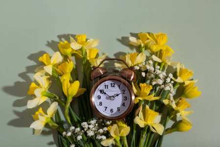 Foto de Reloj despertador con flores de primavera. Primavera, concepto de ahorro de luz natural, primavera hacia adelante. - Imagen libre de derechos